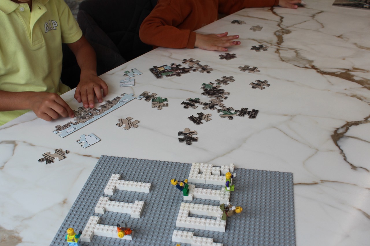 Enfants assemblant le puzzle Kairouan Petit Savoir pendant une activité en famille